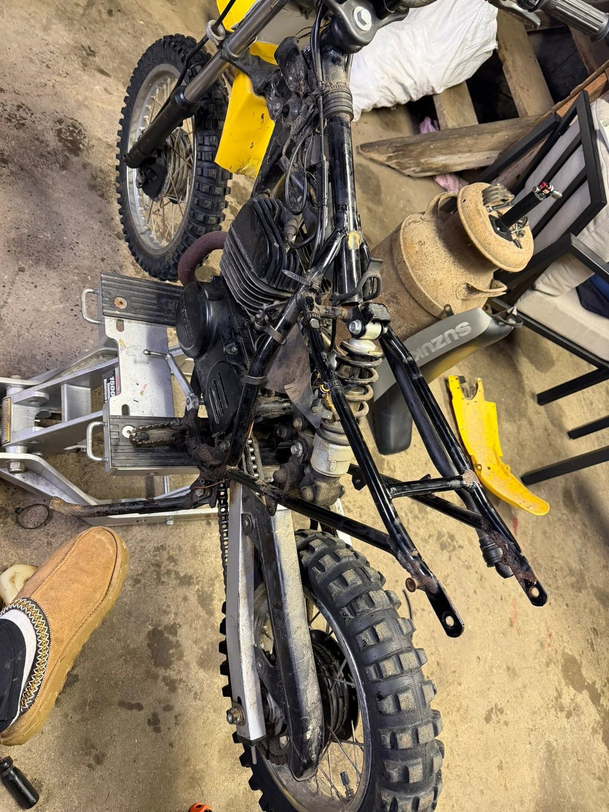 Dirt bike stripped down with parts laid out on the floor