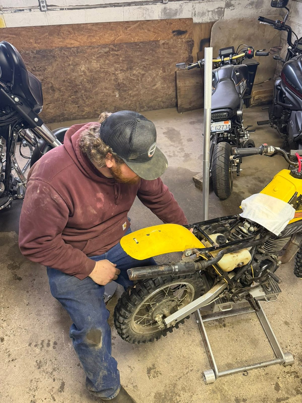 Mechanic working on a yellow dirt bike on a stand
